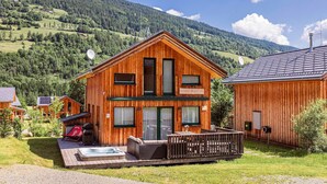 Una cabaña de madera con jacuzzi, terraza y vistas a la montaña.