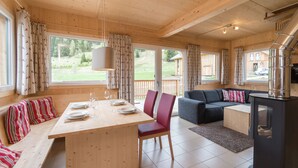 Un interior de madera con una mesa de comedor dispuesta para cuatro personas, un sofá y una chimenea.