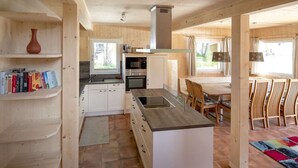 A modern kitchen with white cabinets, a central island, and a dining area with wooden chairs and a table.