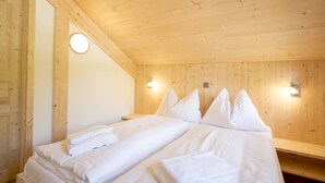 A wooden-paneled room with two beds, each with neatly folded white towels.