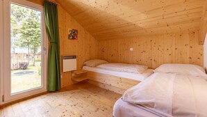 A wooden cabin room with a bed, a window with curtains, and a small shelf. - Appealing chalet in the ski area (Sankt Georgen am Kresichberg)
