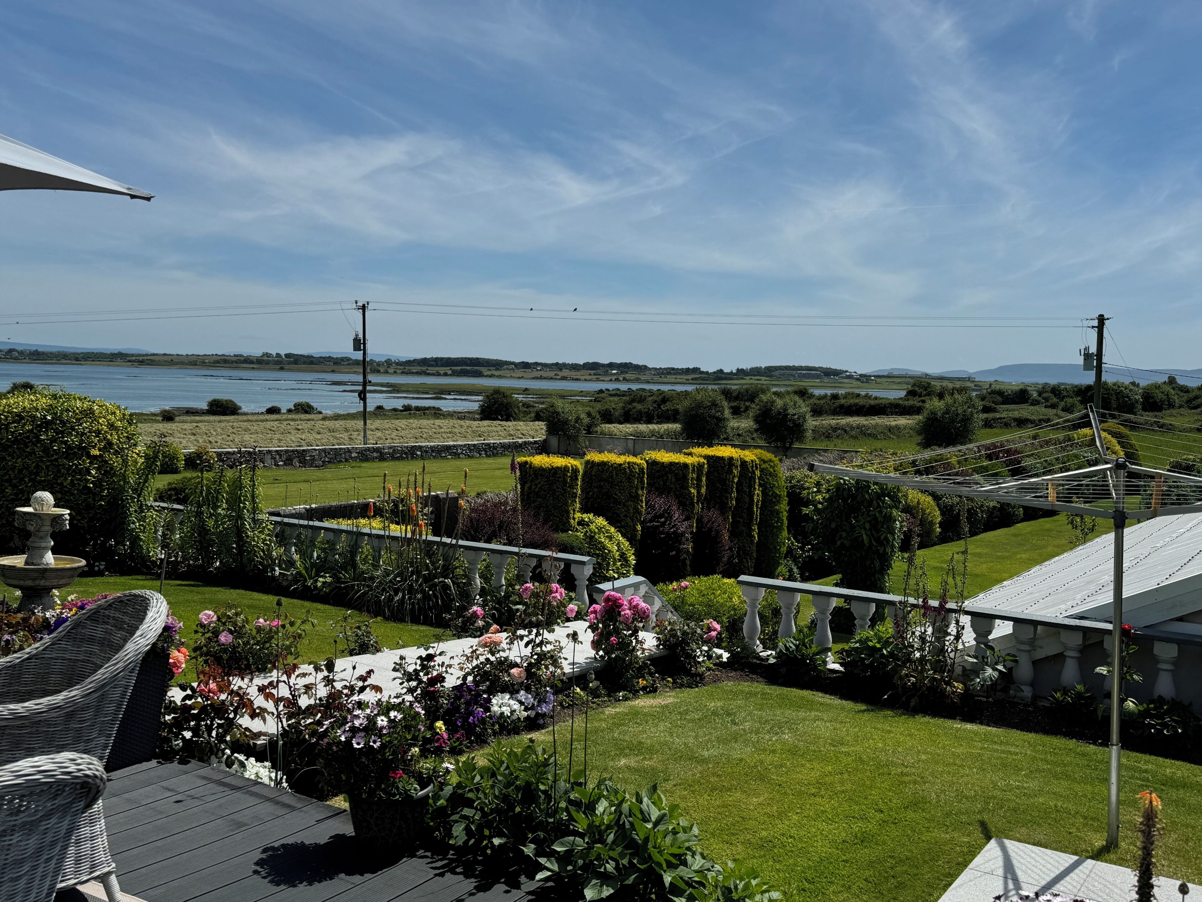 A landscaped garden with a lawn, flower beds, and a view of a lake.