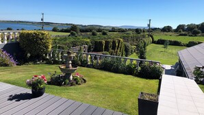 A garden with a fountain, neatly trimmed hedges, and a view of a lake. - Seacrest B&B (Galway)