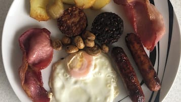 Un plato con diversos alimentos para el desayuno, como huevos, salchichas, tocino y papas.