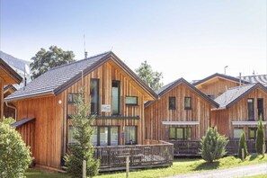 A row of wooden cabins with a balcony, a satellite dish, and a sign indicating a restaurant.