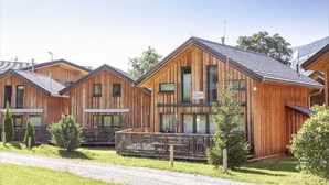 A row of wooden cabins with pitched roofs, large windows, and a gravel driveway.