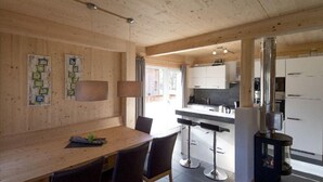 A modern kitchen with white cabinets, a central island, and a dining area with a wooden table and chairs.