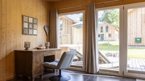 A wooden interior with a desk, chair, and large sliding glass door leading to an outdoor area.