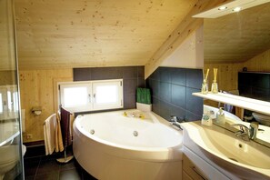 Un baño moderno con una bañera grande, dos lavamanos y un espejo sobre el lavabo.