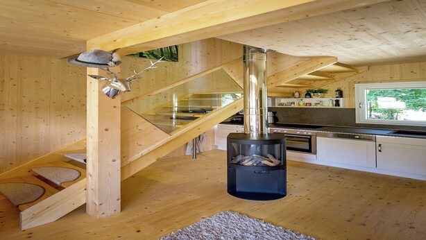 A wooden interior with a kitchen, a fireplace, and a staircase.