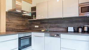 Een moderne keuken met witte kasten, een inbouwoven, een vaatwasser en een magnetron.