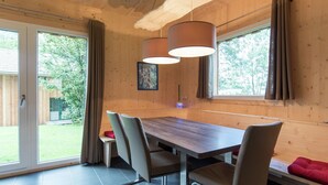Een houten interieur met een eettafel, stoelen en grote ramen.
