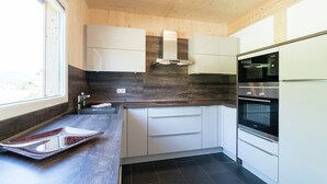Une cuisine moderne avec des meubles blancs, un four en acier inoxydable et un dosseret de carrelage noir.