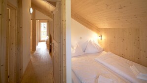 Un intérieur en bois avec un couloir menant à une chambre à coucher équipée d’un lit et d’oreillers.