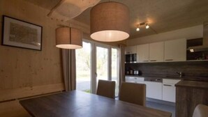 Une cuisine moderne avec des meubles blancs, un plan de travail foncé et des luminaires suspendus.