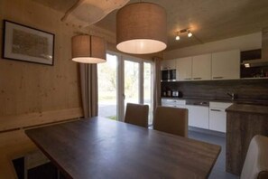 A modern kitchen with white cabinets, a dark countertop, and pendant lighting.