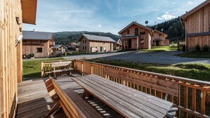 A wooden building complex with a gravel driveway and a wooden deck with benches.