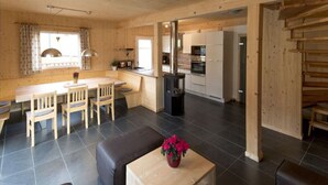 A wooden interior with a dining area, kitchen, and seating space.