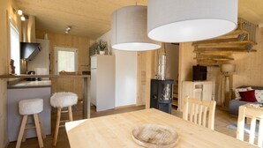 Een moderne keuken met houten details, een eethoek met een houten tafel, en een gezellige woonkamer met een bank en televisie.