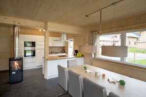 Une cuisine moderne avec un poêle à bois, des armoires blanches et un coin repas comprenant une table et des chaises.
