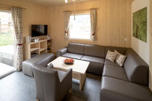 Uma sala de estar moderna com um sofá, uma mesa de centro e uma TV em uma estante de madeira.