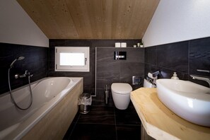A modern bathroom with a bathtub, toilet, and sink. - Charming chalet with whirlpool (Sankt Georgen am Kresichberg)