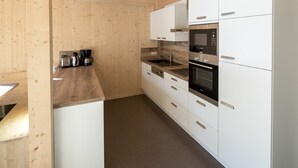 Una cocina moderna con armarios blancos, electrodomésticos de acero inoxidable y encimera de madera.