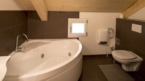 Un baño moderno con una bañera independiente, un inodoro y un secador de manos.