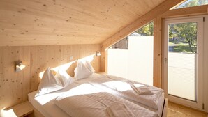 Un dormitorio de cabaña de madera con una cama, almohadas y una mesita de noche.