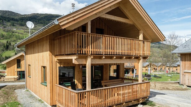Un chalet en bois doté d’un balcon, d’une antenne parabolique et offrant une vue sur le paysage environnant.