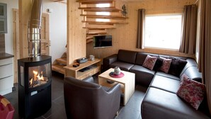 Un salon moderne avec un poêle à bois, un canapé, un téléviseur et une fenêtre avec des rideaux.