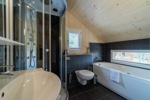 Un baño moderno con una bañera grande, zona de ducha separada y un inodoro.