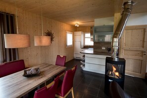 A modern kitchen with a central island, wooden walls, and a wood-burning stove.