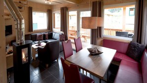 Un intérieur de chalet chaleureux avec une cheminée, des meubles en bois et de grandes fenêtres.