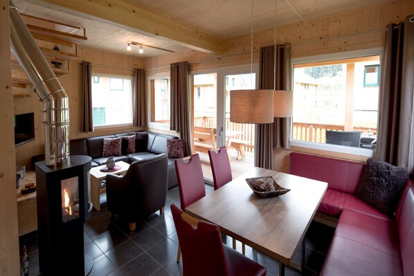 Interior acogedor de una cabaña con chimenea, muebles de madera y ventanas amplias.