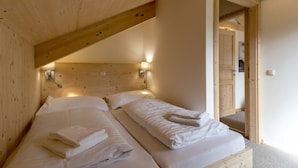 Una habitación de madera con dos camas, cada una con toallas blancas impecables.