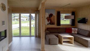 Una sala de estar moderna con un ventanal grande, un sofá, una mesa de centro y un cuadro de una vaca.