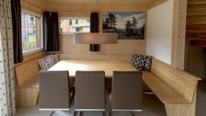 Un interior de madera con una mesa larga, cuatro sillas y un banco.