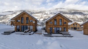 Une cabane en bois avec une grande porte coulissante, un banc et une table à l’extérieur.