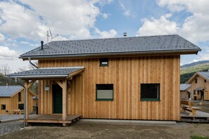 A wooden cabin with a sloped roof, a small porch, and a green door.