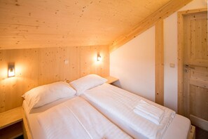 Quarto de madeira com uma cama, duas mesas de cabeceira e uma porta de madeira.