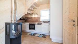 A compact kitchen with a wood-burning stove, white cabinets, and a window.