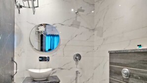 A modern bathroom with a white sink, a round mirror, a toilet, and a shower area. - Hotel The Restu (Amritsar)
