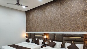 A hotel room with two beds, a ceiling fan, recessed lighting, and a textured wall. - Hotel The Restu (Amritsar)