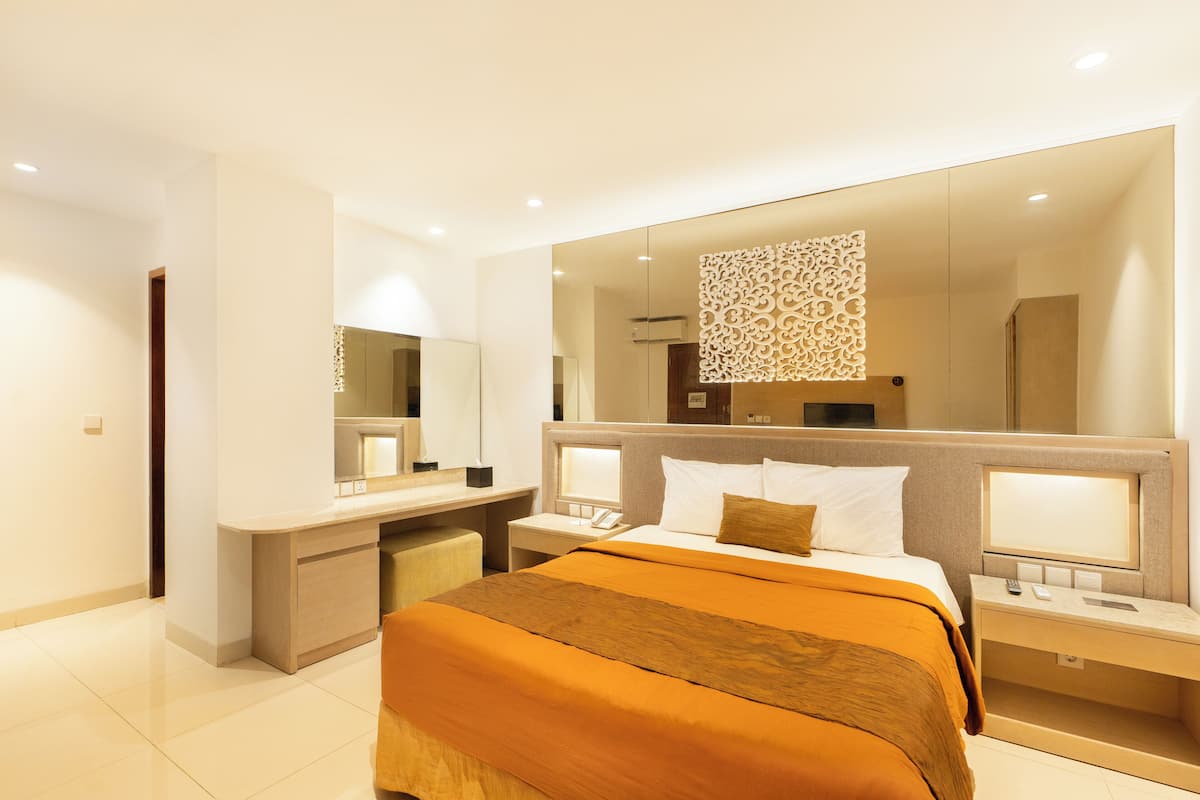 A modern hotel room with a large bed, a desk, and a mirror.