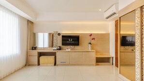 A modern hotel reception area with a wooden desk, a flat-screen TV, and a large mirror. - Kuta Angel Hotel (Kuta)