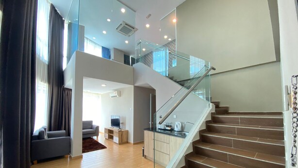 Ein zeitgemäßer Wohnraum mit Treppe, Holzdielen und einem Glasgeländer.