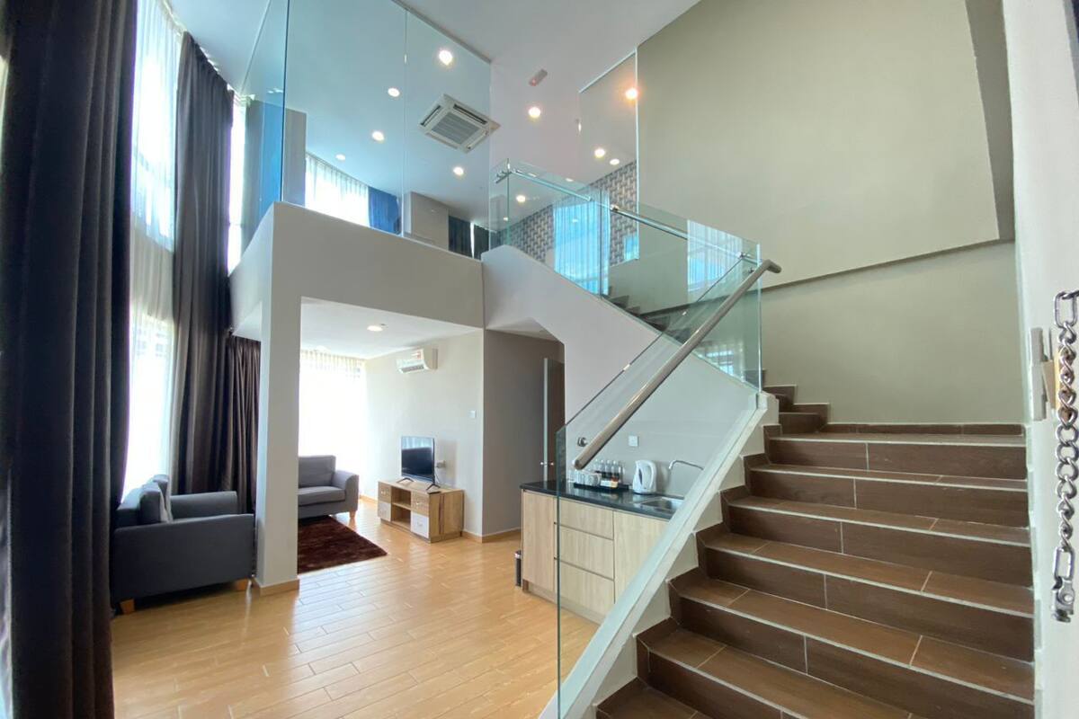 Ein zeitgemäßer Wohnraum mit Treppe, Holzdielen und einem Glasgeländer.