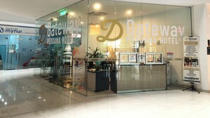 Ein Hotel-Empfangsbereich mit Glaswänden, einer Rezeption und einem Schild für das Gateway Perdana Hotel.