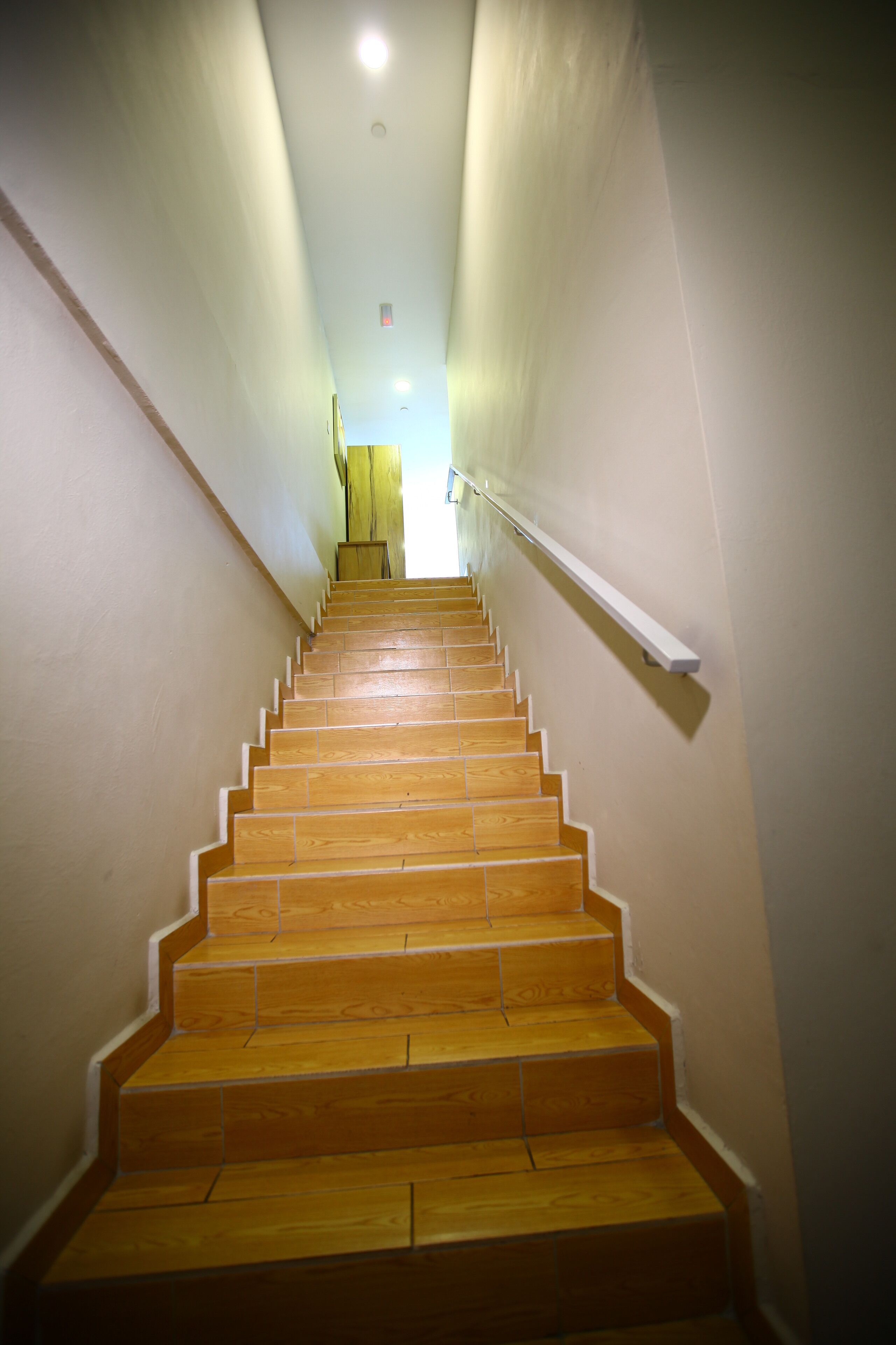 Una escalera de madera con barandilla que lleva a un rellano con una lámpara.